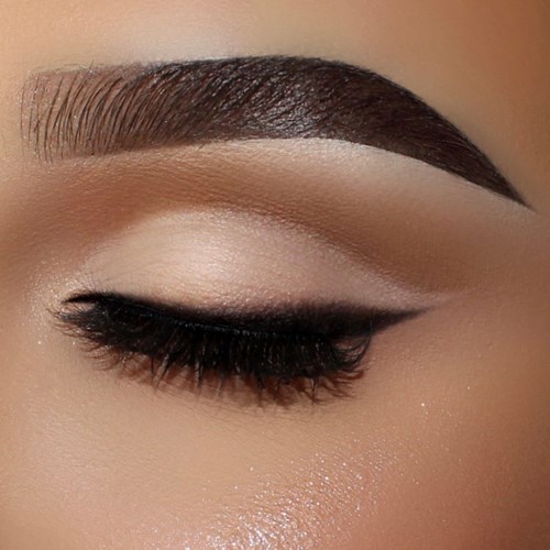 Close-up of a woman's eye with makeup, including eyeliner, eyeshadow, and a well-groomed eyebrow.