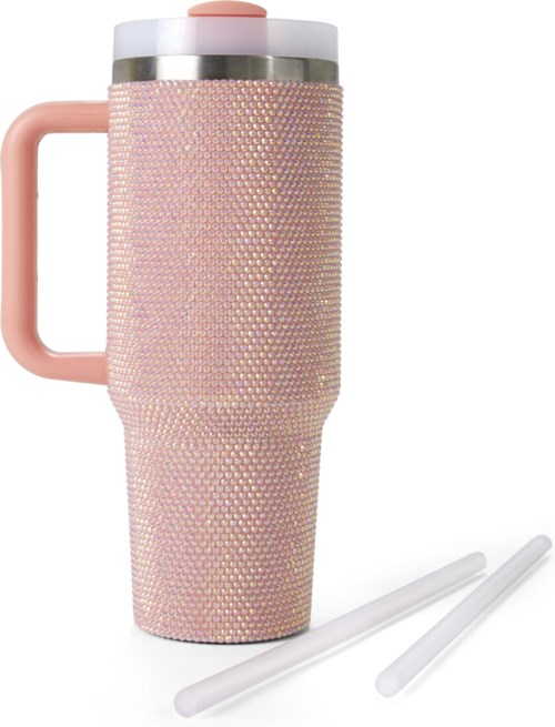 A tall pink travel mug decorated with small beads, with a handle and two straws beside it.