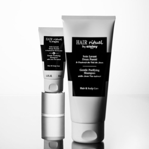 Twee zwart-witte haarverzorgingsflessen, één groot en één klein, met labels over shampoo en hoofdhuidverzorging.