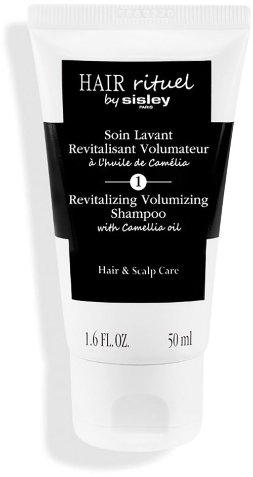 A white bottle with black label, green cap, and text about a revitalizing volumizing shampoo with Camellia oil.