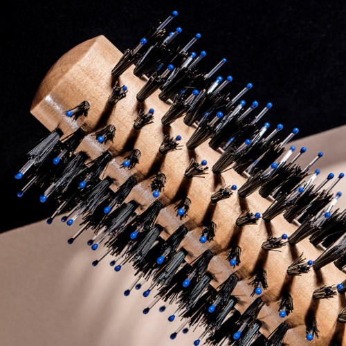 Een houten borstel met veel zwarte pinnen en blauwe punten, gebruikt voor haar of hoofdhuid.
