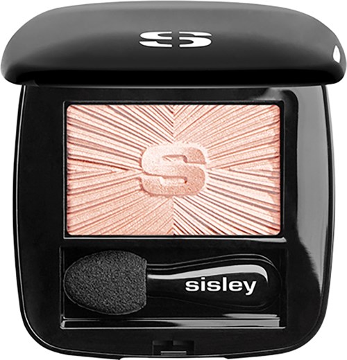 A black compact with a blush inside, showing a sunburst pattern and the letter 'S'. It includes a small brush.
