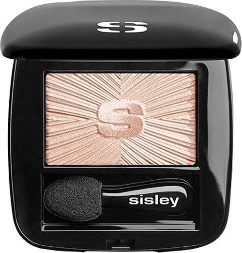 A black compact with a glowing S logo, a highlighter inside, and a small applicator brush. Bright, shimmery makeup product.