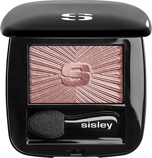A makeup compact with a pinkish blush, a black sponge applicator, and a logo on the lid.