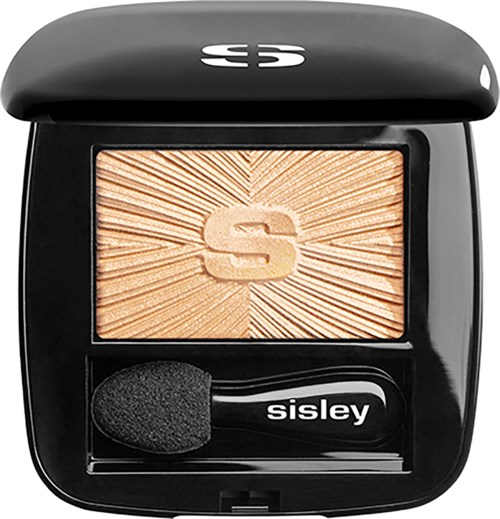 A compact with beige powder that has a large 'S' embossed, and a small black sponge applicator inside.