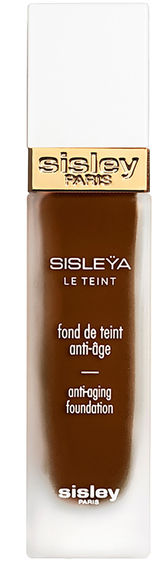 A bottle of Sisley Yves anti-aging foundation with a white cap, gold band, and brown liquid inside.