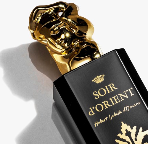 A black perfume bottle with a gold decorative cap, labeled "SOIR d'ORIENT" by Hubert Isabell d'Oman.