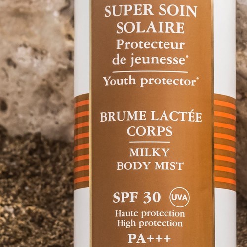 Een fles met zonnebrandlabel: SPF 30, hoge bescherming, jeugd- en bodymelk, UVA-bescherming, bruin en wit ontwerp.