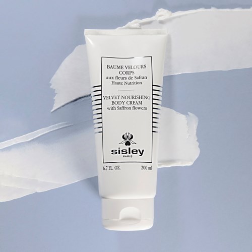En hvit tube med Sisley velvet nærende kroppskrem med safranblomster på en hvit bakgrunn.