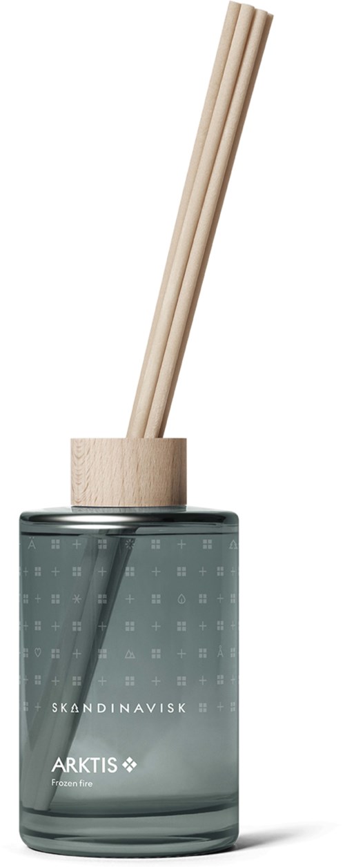Ein dunkler Glasbehälter mit Holzstäbchen, beschriftet mit skandinavischen Marken, als Diffusor verwendet.