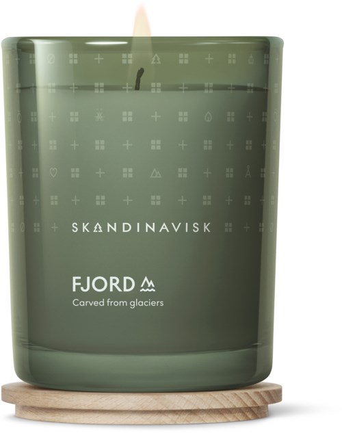 Eine grüne Kerze mit 'Skandinavisk' und 'Fjord', auf einer Holzunterlage.