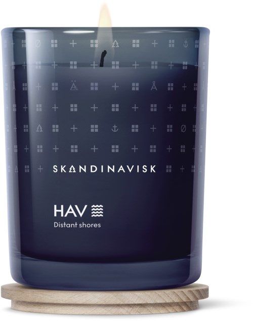 En mörkblå doftljus med skandinaviska symboler och orden 'HAV Distant shores' på etiketten, placerad på en träram.