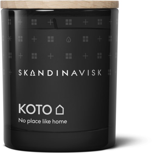 Eine schwarze Kerze mit einem Holzdeckel. Das Etikett sagt "KOTO" und "No place like home."