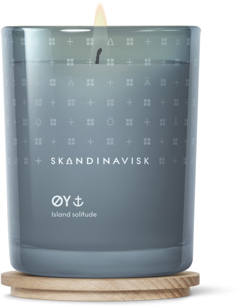 Eine graue Kerze in einem Glas auf einem Holzsockel, beschriftet 'Island solitude' von Skandinavisk, mit schwarzem Docht.