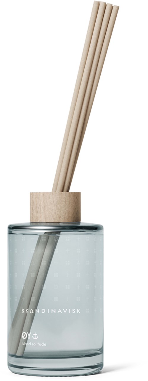 A clear glass diffuser bottle with three beige sticks inside. The bottle has text "SKANDINAVISK" on it.