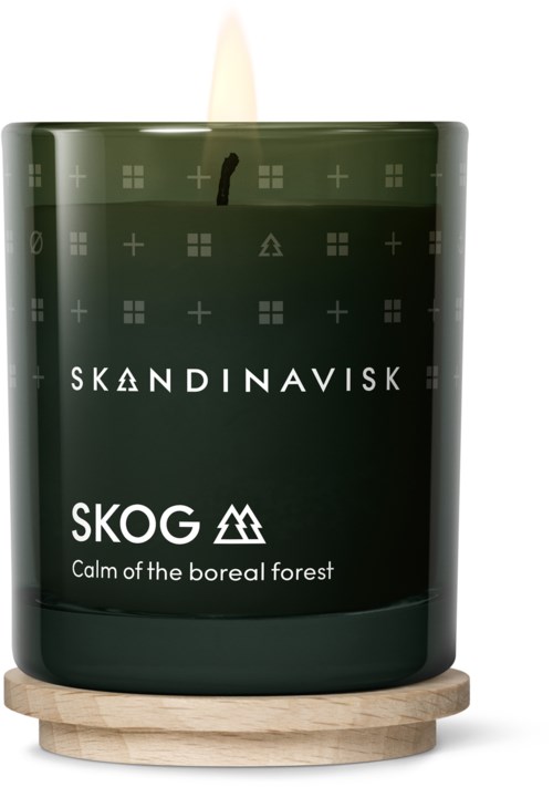 Eine dunkelgrüne Duftkerze in einem Glas mit skandinavischem Design, beschriftet 'SKOG', auf einer Holzbasis.