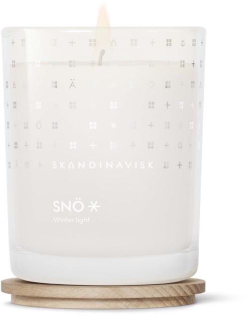 Eine weiße Kerze in einem Glas, beschriftet 'Skandinavisk' und 'Snö Winter Light', auf einer Holzwechsel.