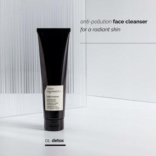 A black tube of face cleanser with a white label, standing on a light background. Text mentions anti-pollution and radiant skin.