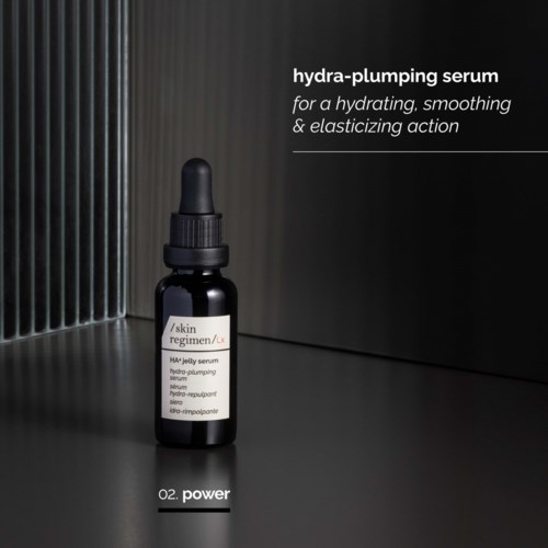 A small black dropper bottle labeled 'HA-jelly serum' stands on a dark surface with a textured gray background.