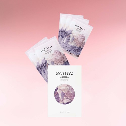 Drei Gesichtsmasken und eine Packung mit Berg- und Lila-Design auf rosa Hintergrund.