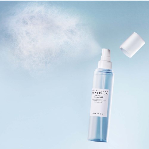 Eine klare Sprühflasche gibt einen feinen Nebel ab vor einem hellblauen Hintergrund.