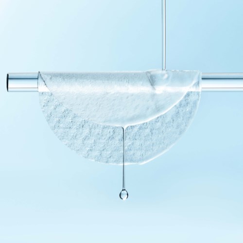 A test tube with a round clear dish below catching liquid drips, against a light blue background.