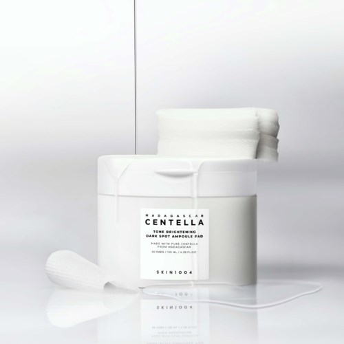 A white jar of brightening face cream with the label visible, accompanied by a small white applicator and some cream.