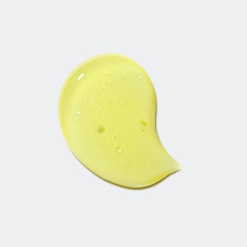 Een gele druppel met kleine bellen, lijkt op een spetter of vloeistofvlek.