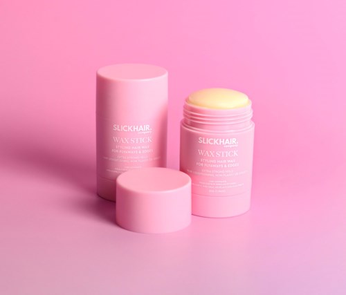 Twee roze containers van wasstift, eentje open met gele was, de andere dicht, op een roze achtergrond.