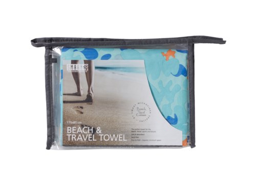 En klar plastpåse med svart kant, innehåller en strand- och resehandduk, med en strandbild på etiketten.