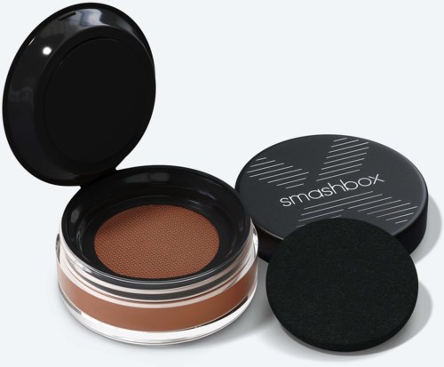 A container of brown makeup with a sponge, a black lid with "smashbox" written on it, and a black applicator.