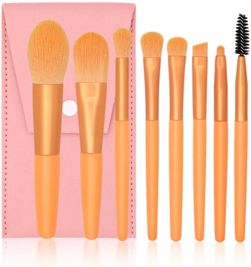 Set of seven makeup brushes with orange handles, including powder, blush, eyeshadow, and mascara brushes, with pink case.