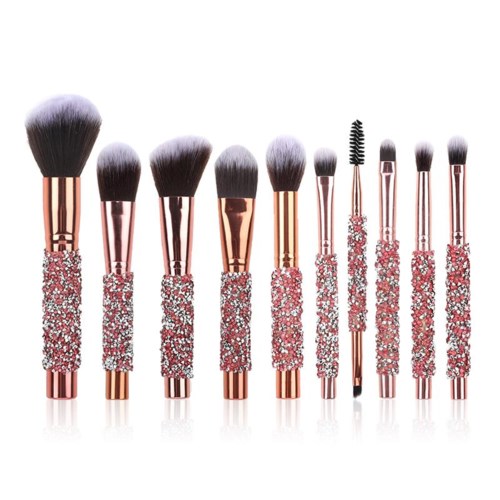 A set of makeup brushes with pink and silver handles, decorated with rhinestones, arranged in a row.