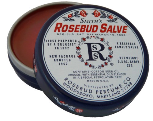 Pyöreä rasiakangas, jossa lukee 'Smith's Rosebud Salve' logo ja teksti, käytetään ihonhoitotuotteena. Tietoja yrityksestä ja aineosista.