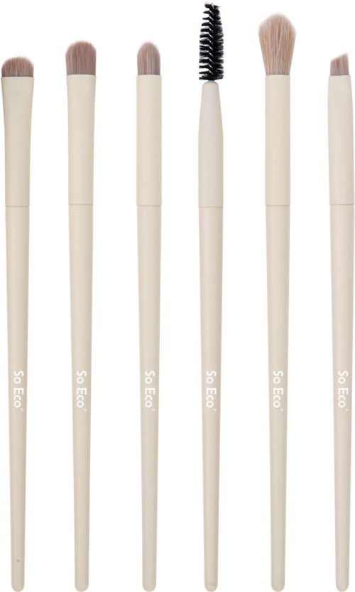 Six makeup brushes with beige handles and different shaped brush heads. One brush has a black spoolie. All are lined up neatly.