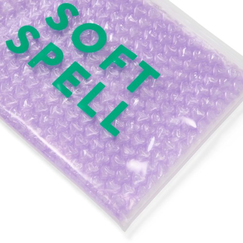 A purple bubble wrap package with green text saying "SOT SPÉL" on it.
