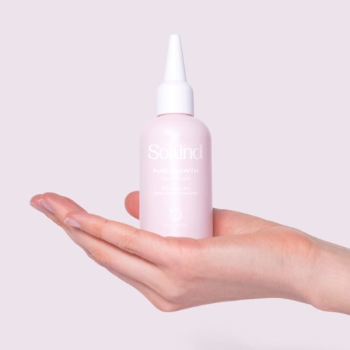 Eine Hand hält eine rosa Flasche mit weißer Spitze, beschriftet 'Solid'. Der Hintergrund ist hell und schlicht.