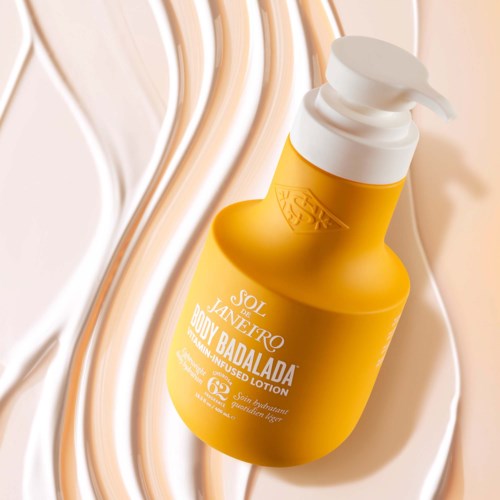 Gelbe Lotionflasche mit weißem Pumpkopf auf strukturiertem weißen Hintergrund.