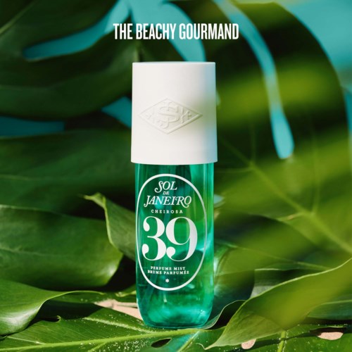 A perfume spray bottle with green liquid and white cap, surrounded by tropical green leaves, labeled Sol de Janeiro 39.