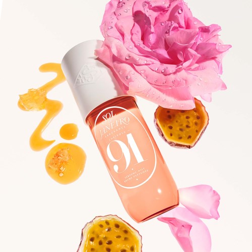 Eine pinke Blume, Passionsfrucht-Hälften und eine Flasche Hautpflege-Serum mit Tropfen um sie herum.