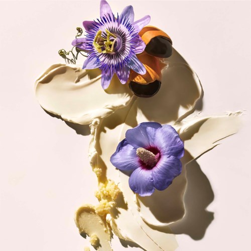 Sahnige weiße Nachspeise mit lila und orange Blumen, und einem Marienkäfer auf einem Blatt.