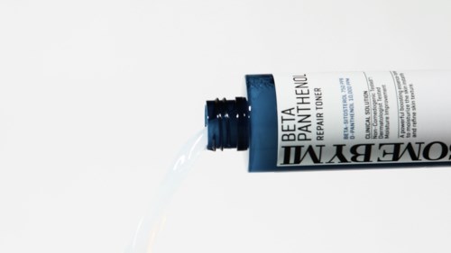 A tube of skincare cream labeled 'Beta PATA ITHENOL' is lying on its side with some cream coming out.
