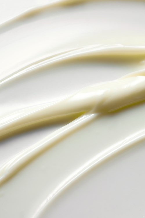Cream or sauce spread with smooth, curved lines on a white surface.