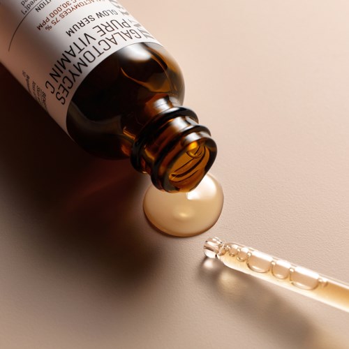 A brown bottle labeled 'galactomannan' with a dropper releasing a drop, set on a light background.