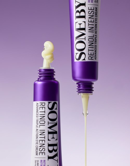 Twee paarse tubes huidverzorgingsproduct, waarvan één geopend met crème en pipet. Achtergrond is verlooppaars.