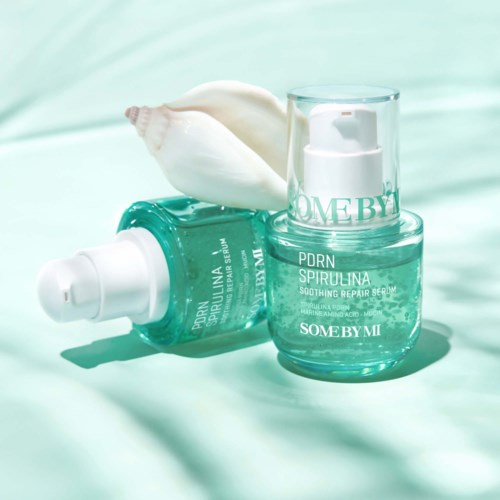 Light blue skincare bottles and jars with white seashells against a soft background.