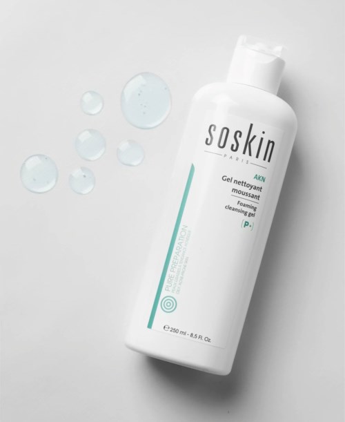 A white bottle of Soskin cleansing gel with blue text and droplets of gel nearby.