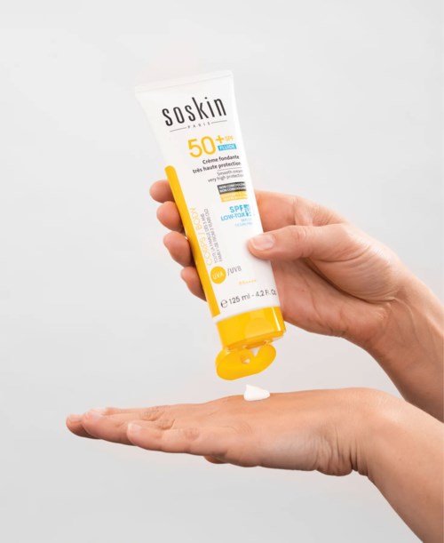 A hand squeezes out sunscreen labeled SPF 50 from a tube onto the other hand.