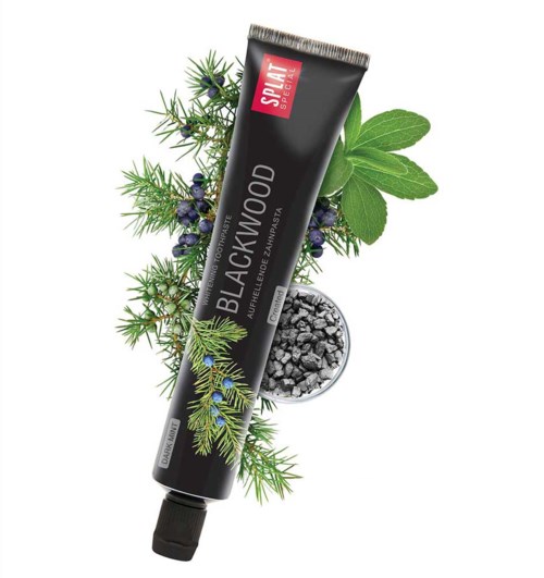 A tube labeled 'Blackwood' is surrounded by green leaves, small black berries, and black charcoal pieces.