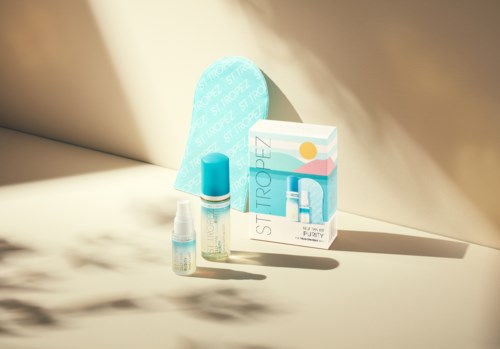 Ein Hautpflegeset mit Flasche, Pumpspender und einer Box mit "Purely" und "Sti Tropez" auf heller Oberfläche.